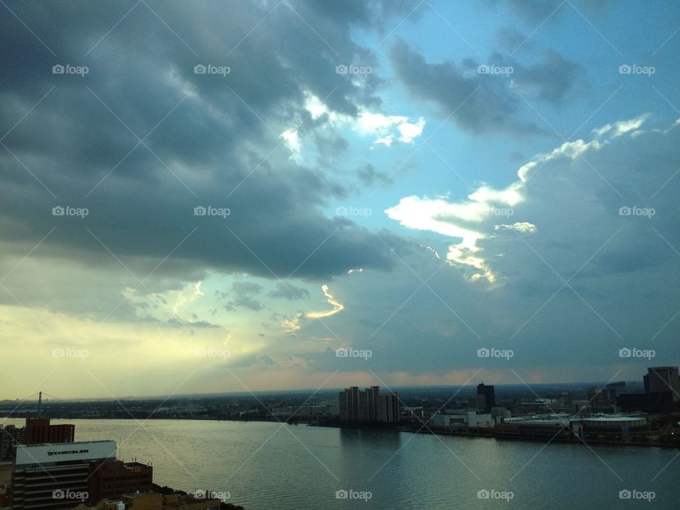 Storm clouds with blue sky. A view from Canada over the Detroit river with a patch of blue sky amidst the storm clouds near sunset.