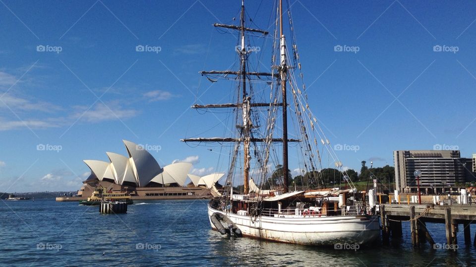 A historic ship floating in Sydney Harbour, with the iconic Sydney Opera House visible in the background. 