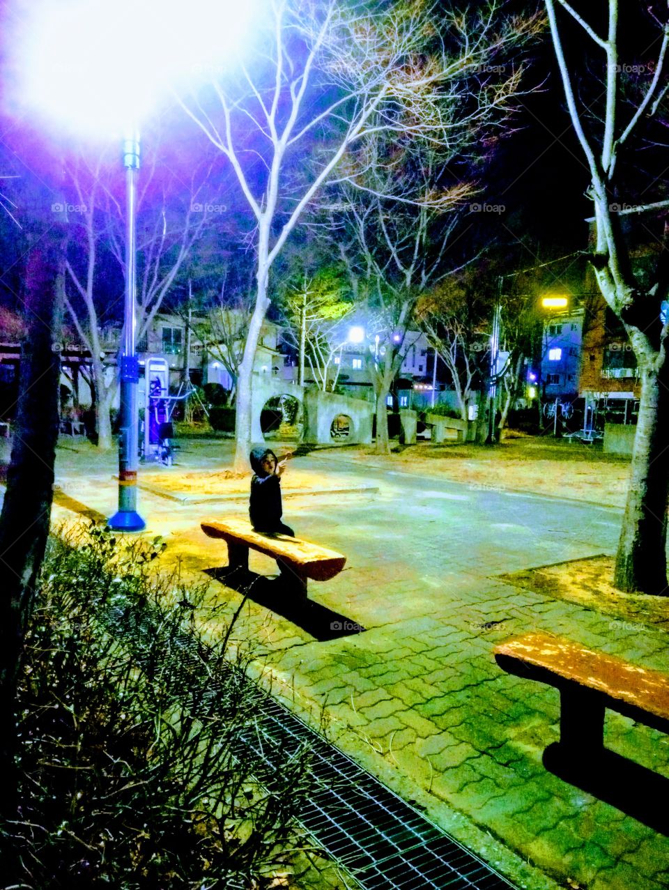 The winter nights at the country park.
The little boy sitting on the bench to feel the fresh air and to smell  the winter scent at night.
