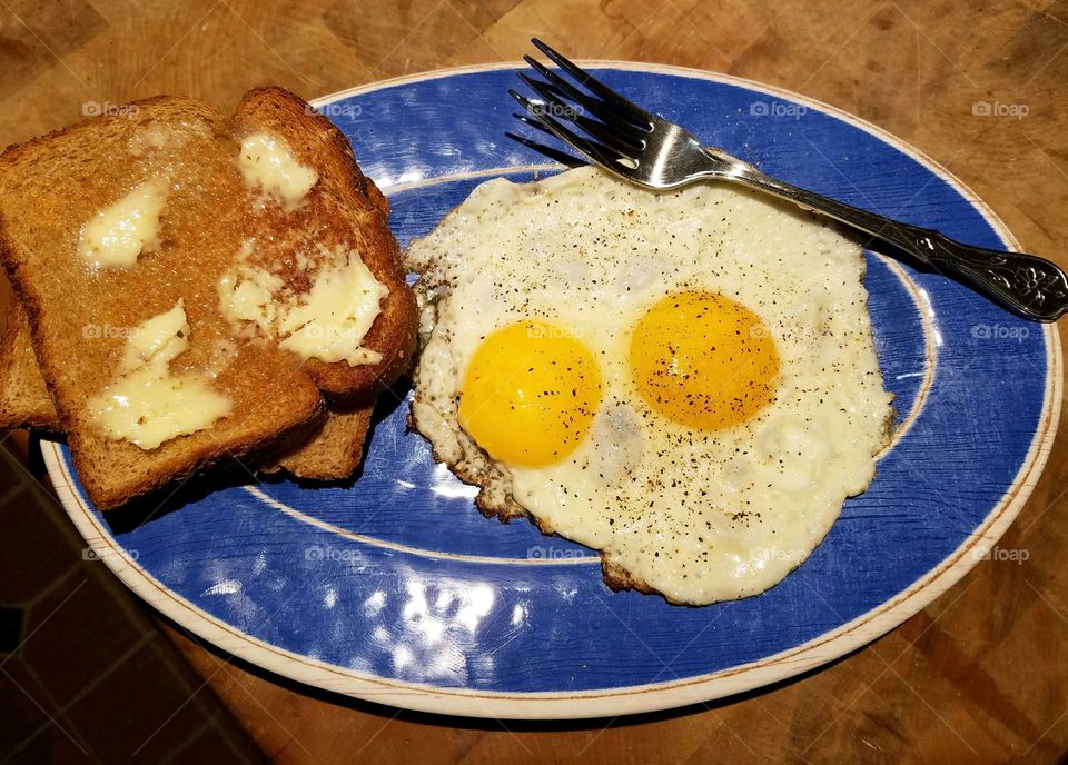 Sunny side up eggs, with buttered toast & sprinkled with ground pepper. Blue plate special!