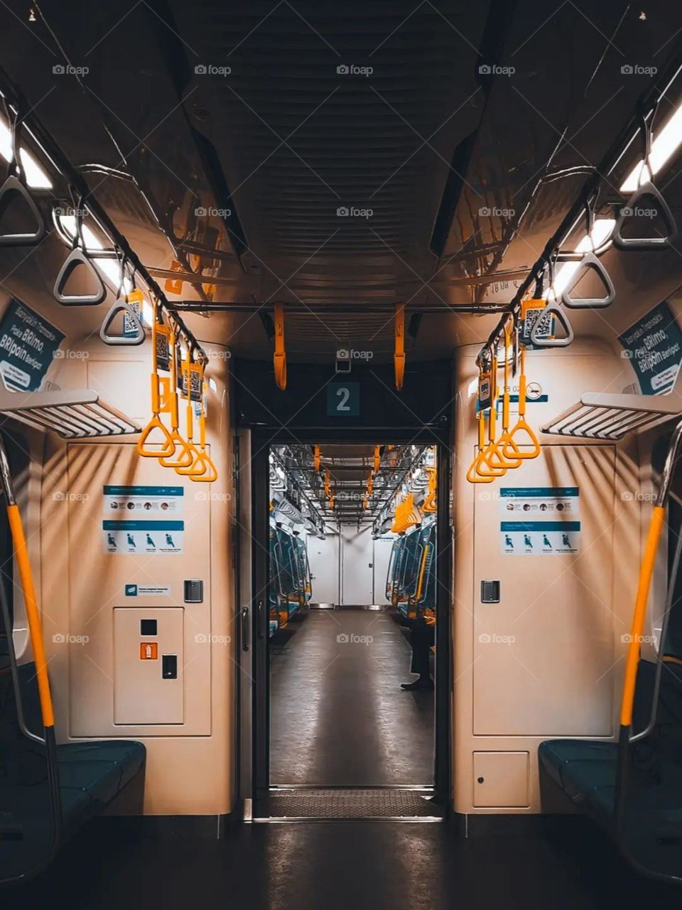 Portrait of an empty subway train interior with warm lighting, blue seats and yellow handrails