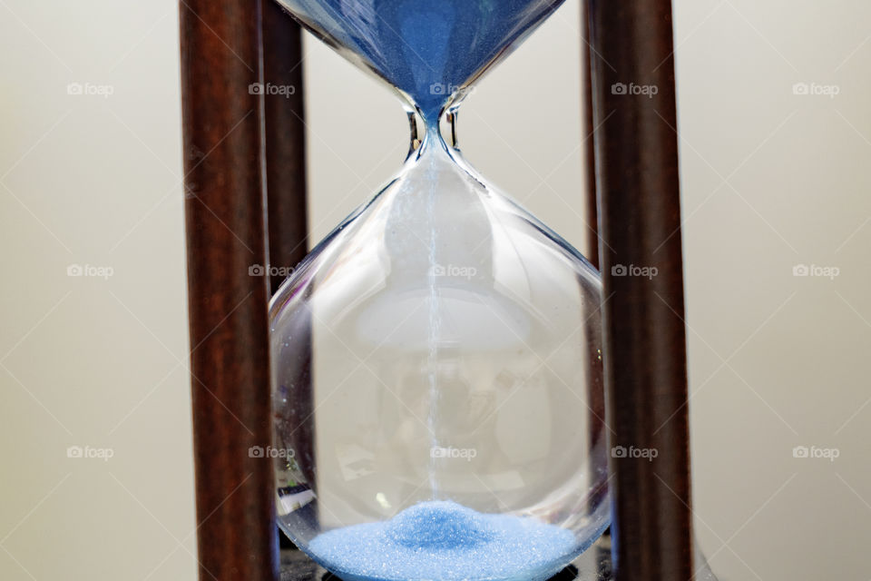 Blue sand dropping in the hourglass
