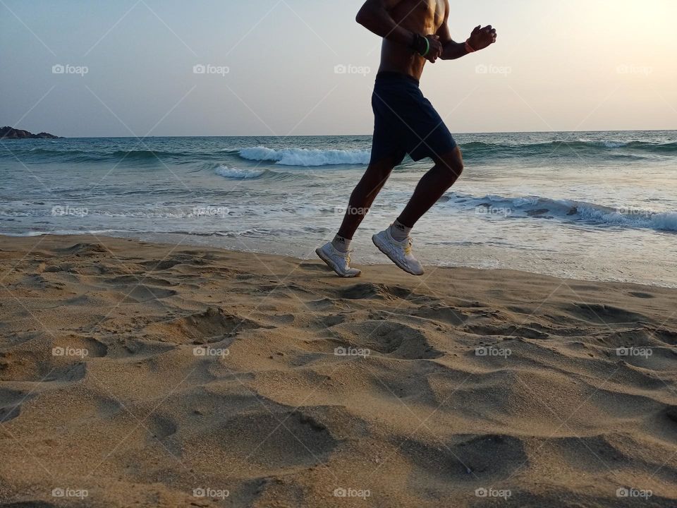 Running man jogging at beach during fitness in evening