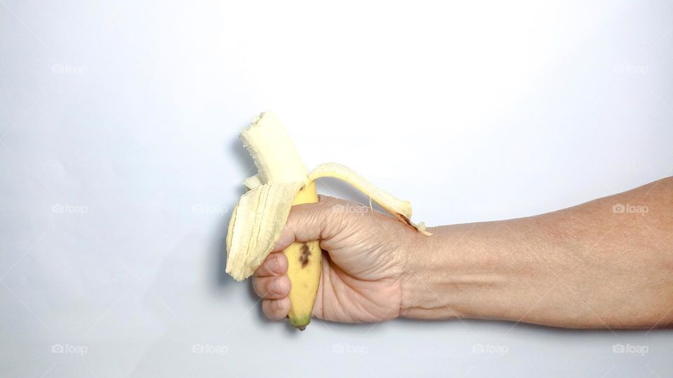 The hand is holding an open and bitten banana in eye level view