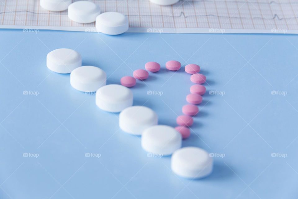 Pills and medicines lie on a blue background with an electrocardiogram of the heart.