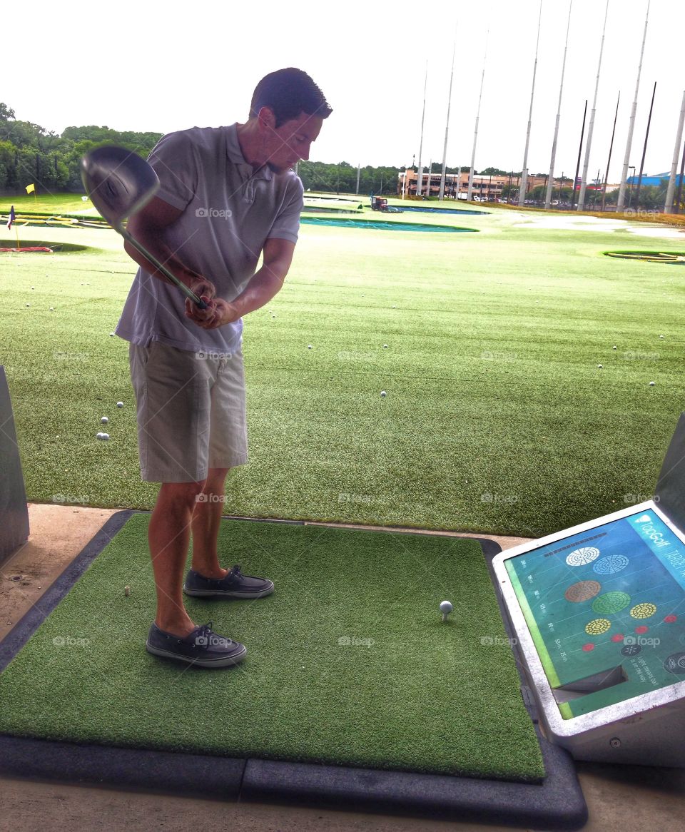 Swing that club!. Man golfing at Top Golf