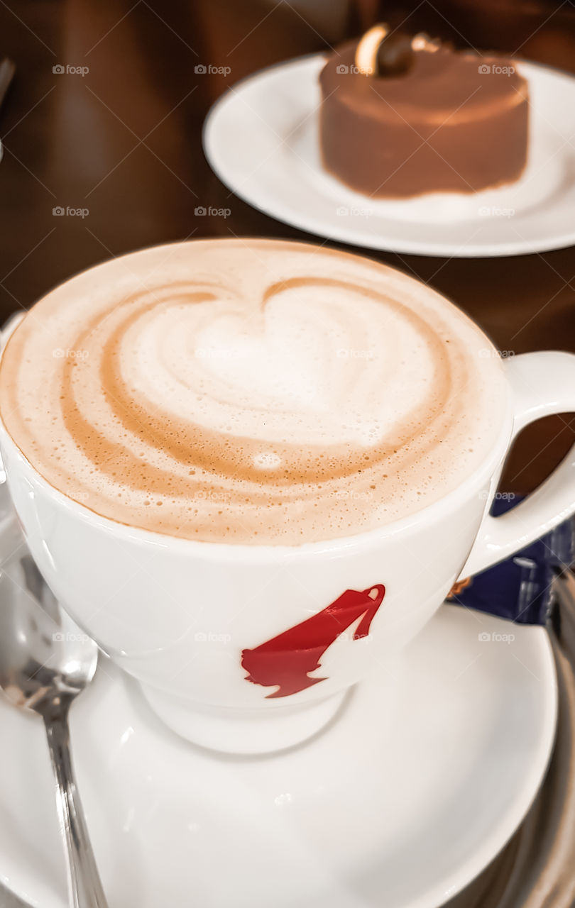 Selective focus to white cup with cappuccino on the table.