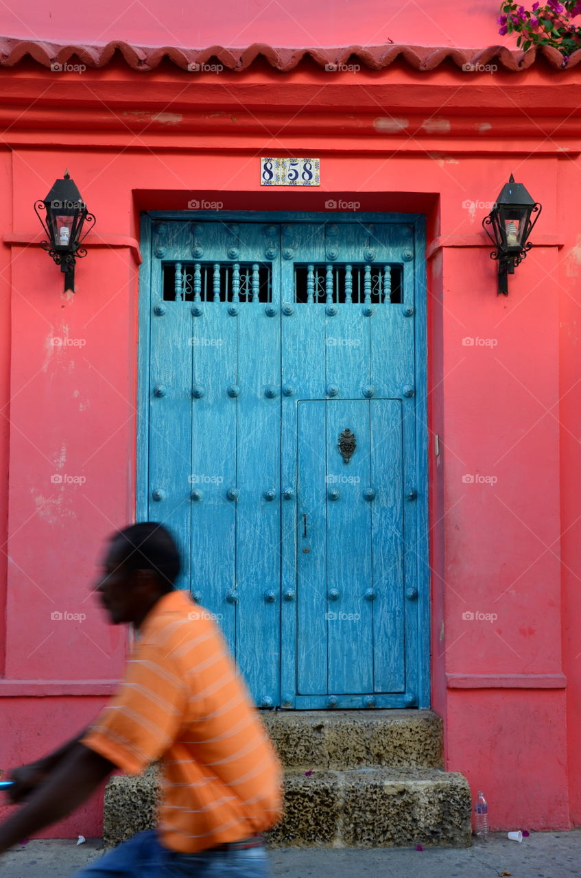 Red house with blue door and man with orange shirt