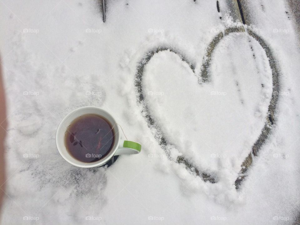 Cup of coffee with heart shape on snow