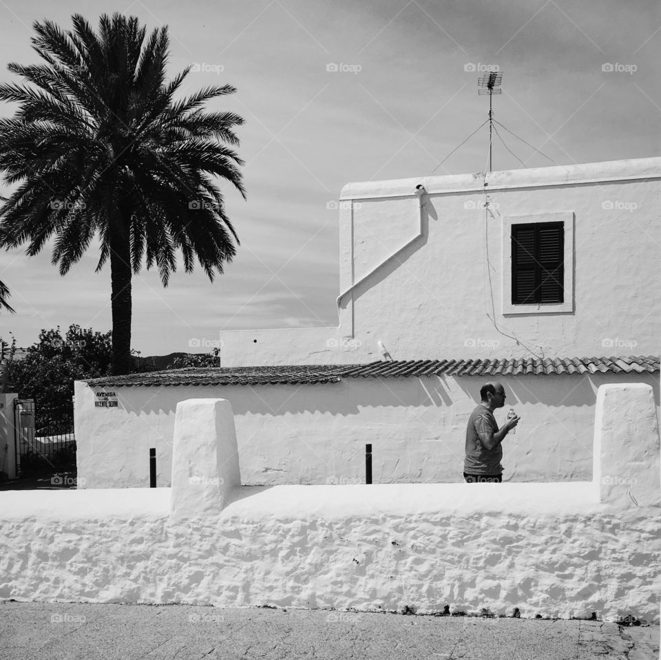 Man walking around passing white wall