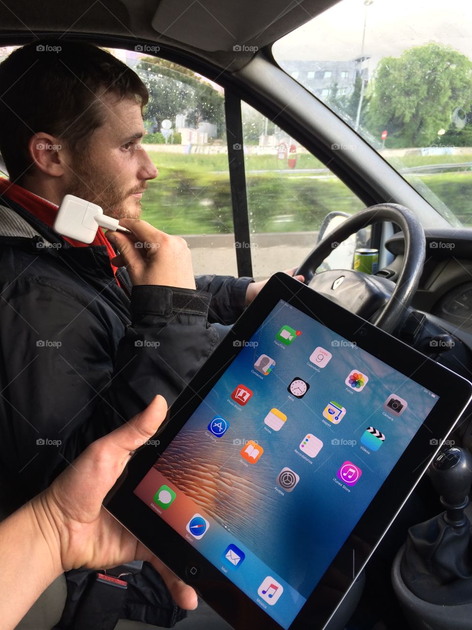 Guy driving while copilot use iPad tablet 