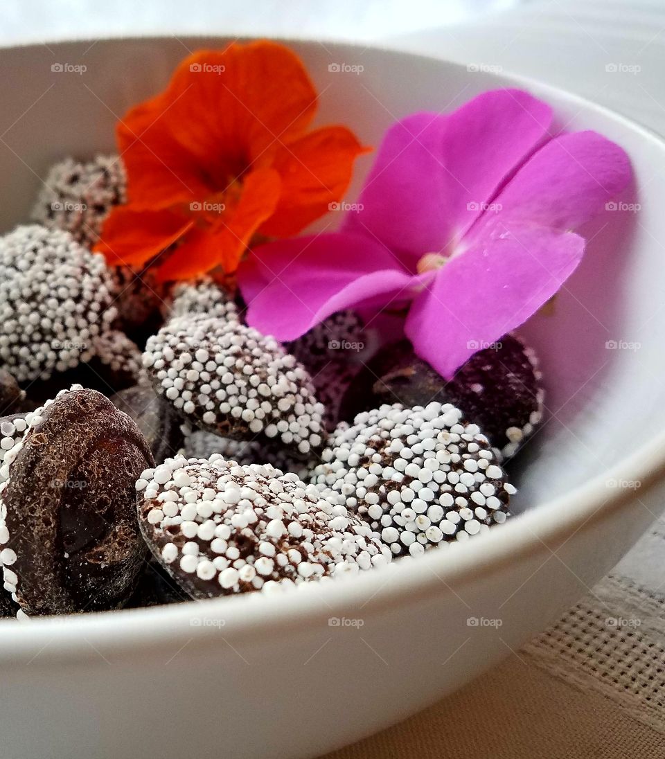white bowl of chocolate non-pareilles with pink and orange flowers