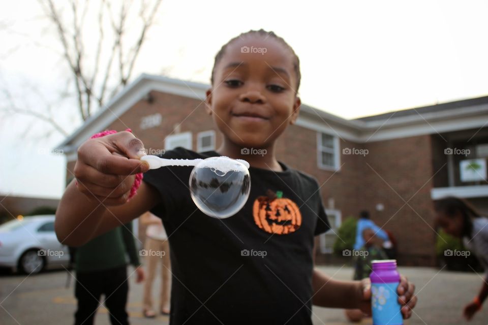 girl with bubble. a young refugee girl plays with bubbles outside 