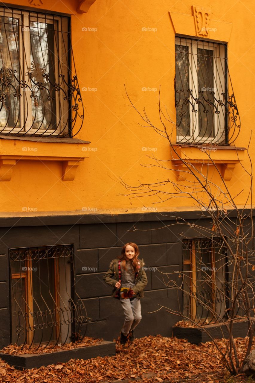 Girl jumping near the house painted in yellow and black