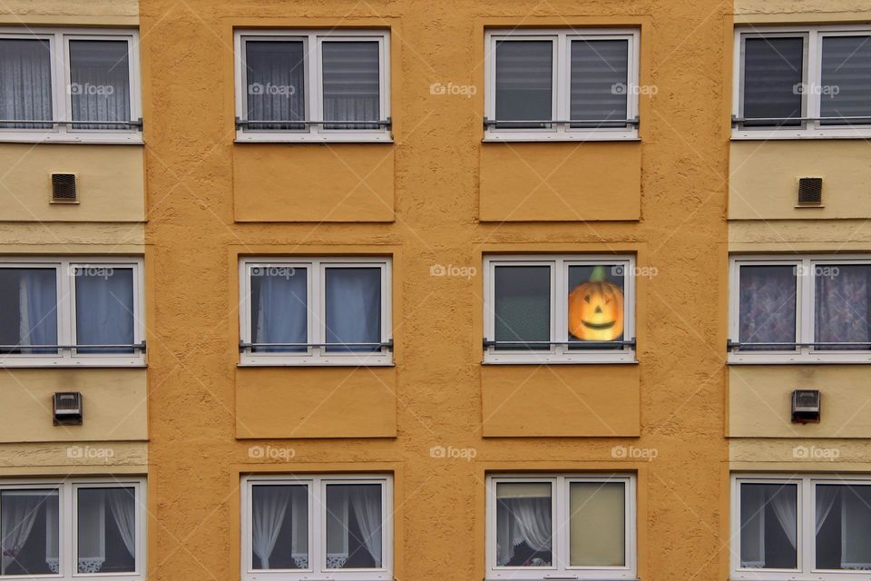 The orange face of a Halloween pumpkin on a window in an orange house