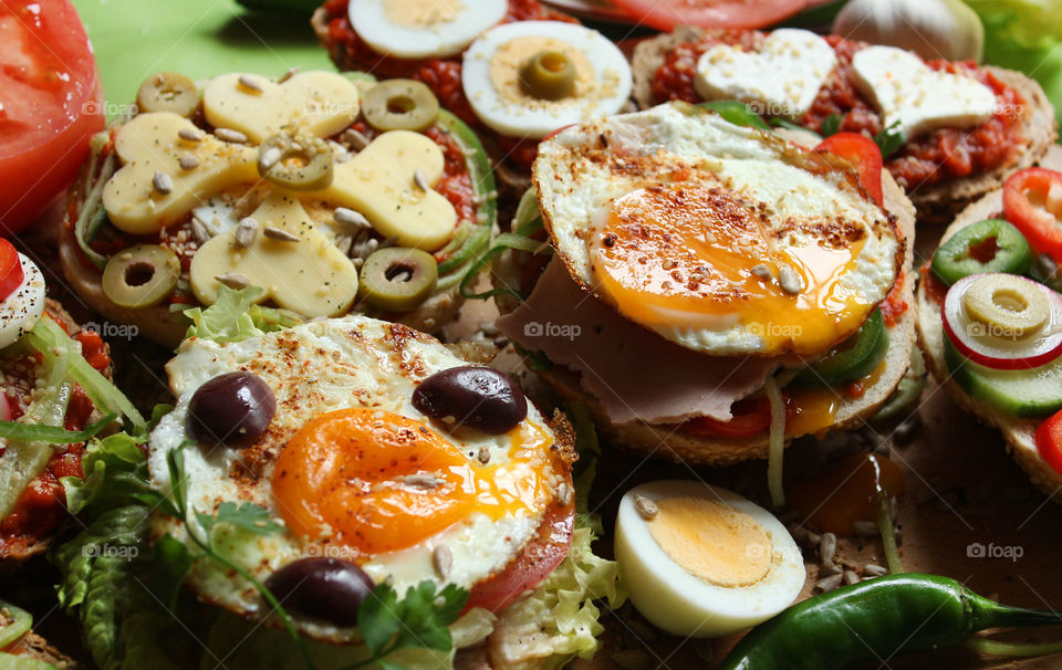Sandwiches with eggs, yellow cheese, olives, lettuce