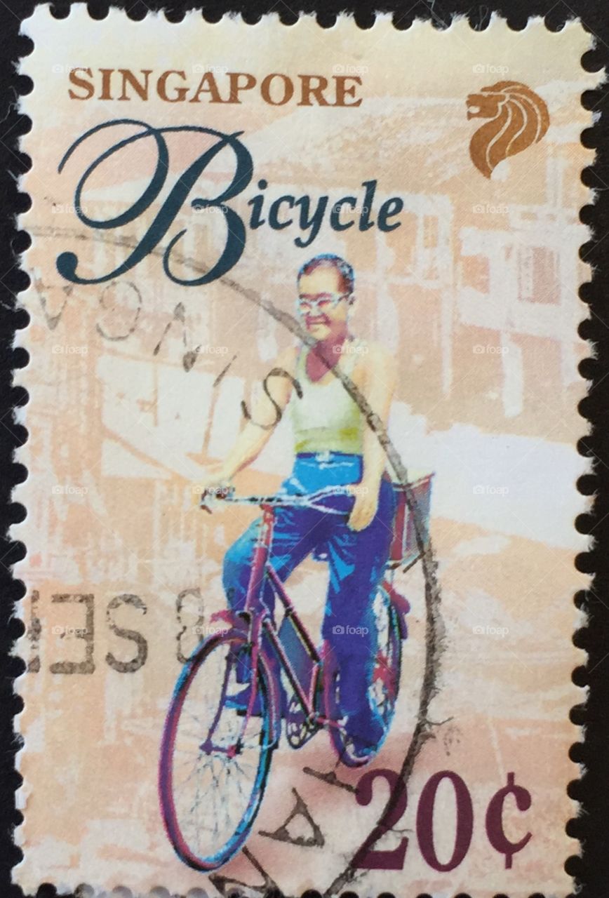 Singapore stamp of man on a bicycle with lion emblem in top right corner