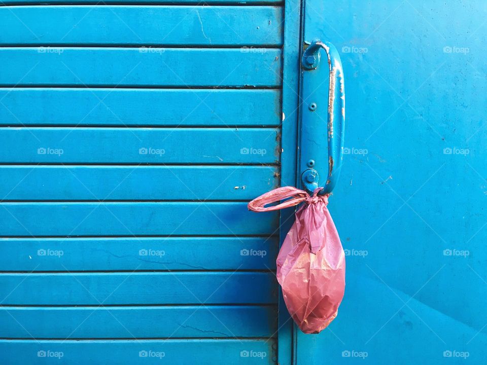 Pink bag on blue door handle texture background 