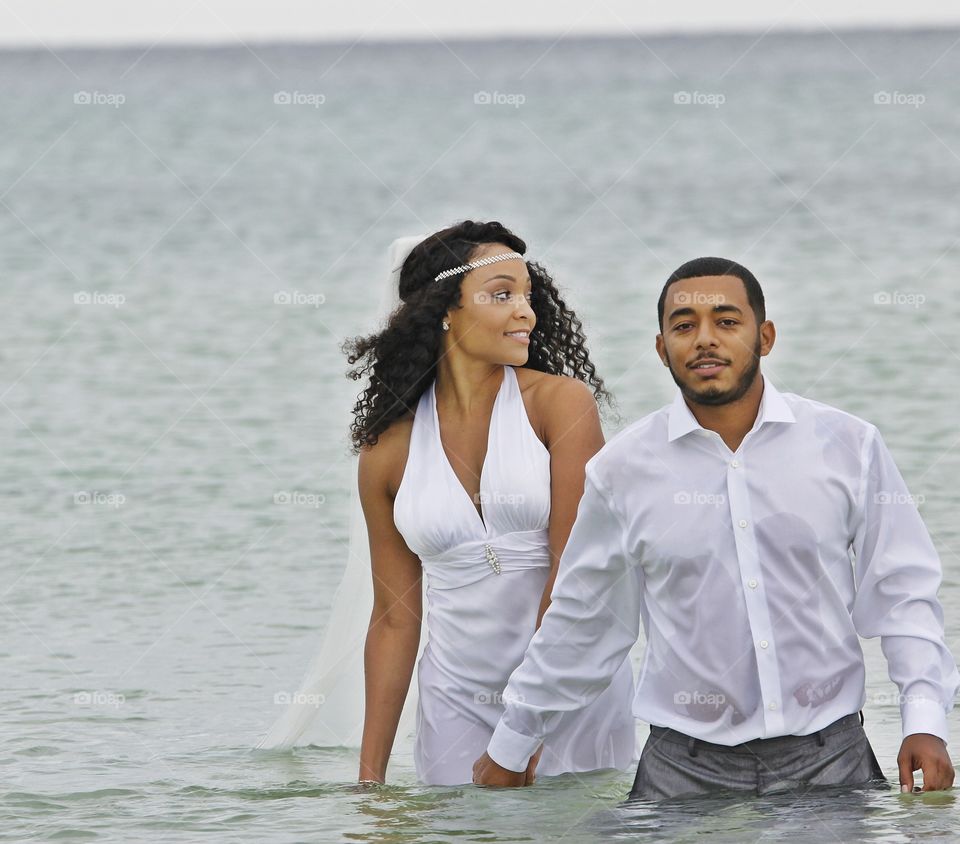 Newly wed couple walking in sea