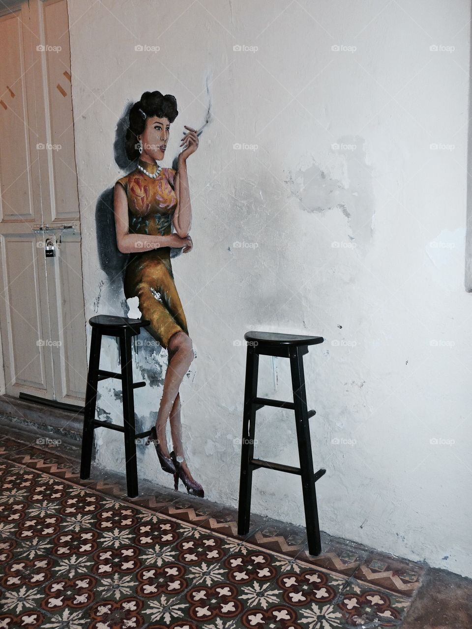 Woman sitting on a bar stool. Georgetown (Penang) is full of beautiful paintings and art. The painted woman who is waiting for a loved one.