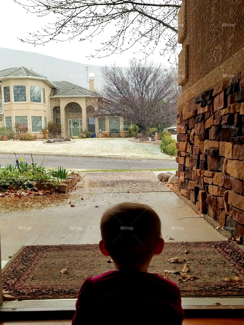 Baby girl sitting in doorway watching it snow outside