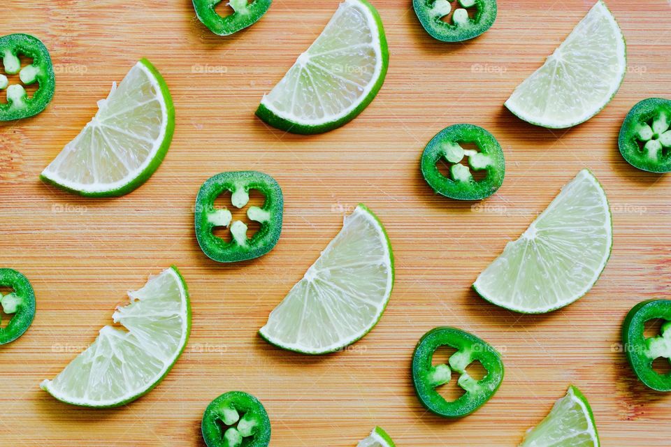 Flat lay of lime and jalapeño slices arranged on a bamboo cutting board