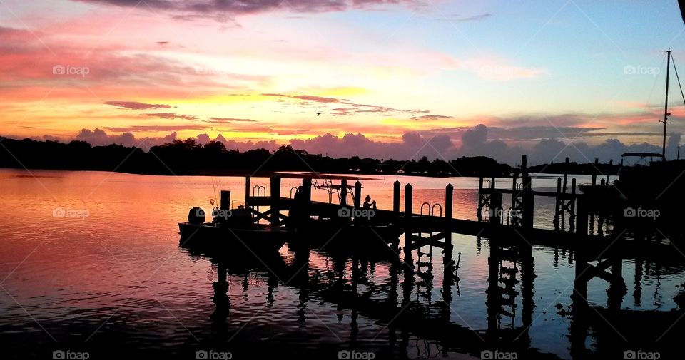 Beautiful sunset overlooking the water,  with boats pulled up to dock at the restaurant