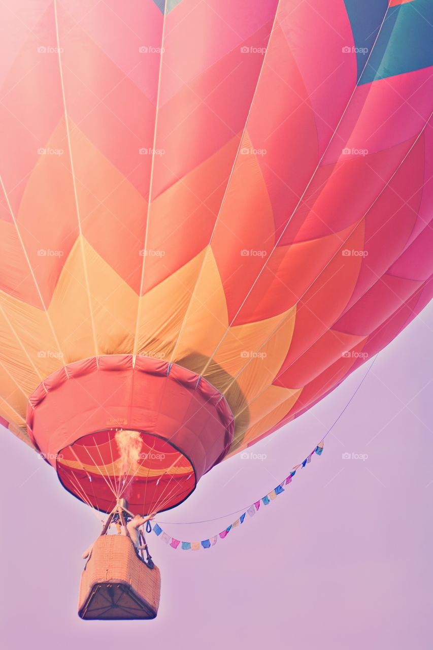 Hot air balloon in the summer sky. Pink, yellow, and orange stripes and colorful flags decorate the sky.