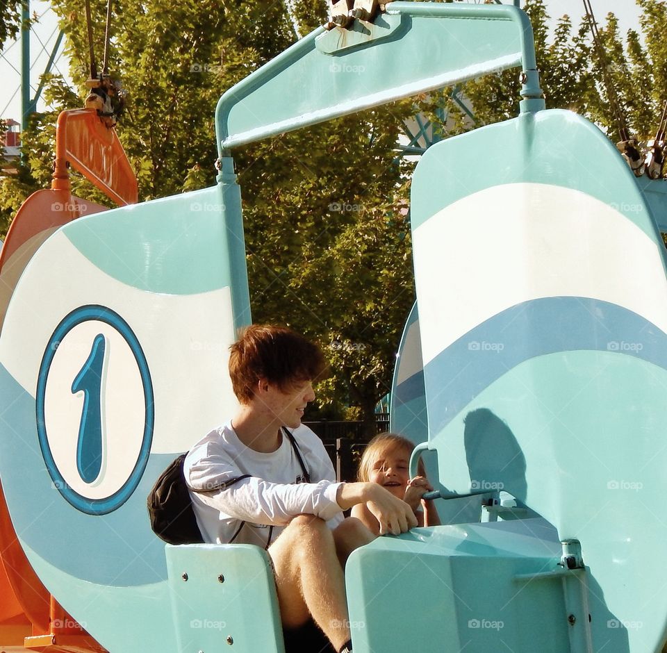 cousins share a ride at the amusement park.