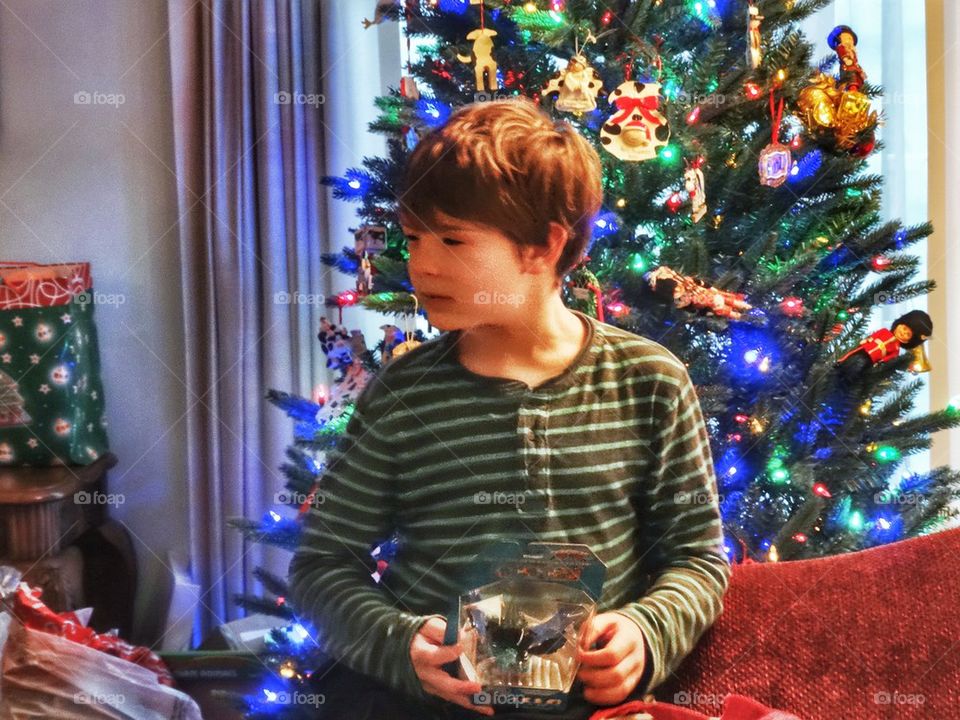 Opening Presents Christmas Morning. Young Boy Waiting To Open Presents By The Christmas Tree
