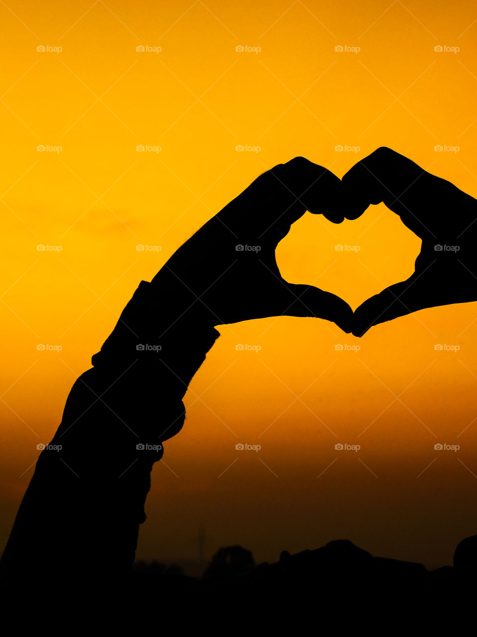 Love wallpaper or heart shaped hand posture with beautiful background of after sunset golden light .