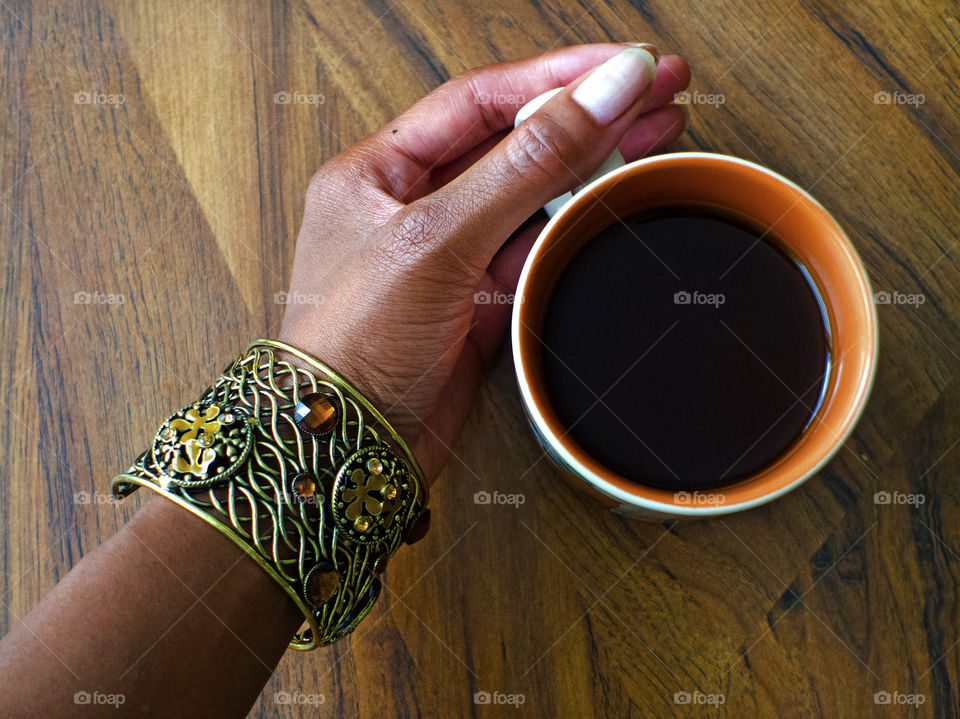 Holding a cup of tea on a wood table.