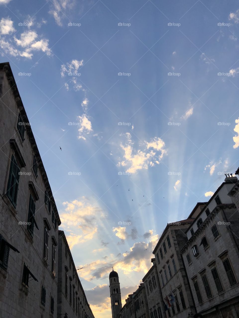 Beautiful blue sky with some scattered clouds and sun rays in the city of Dubrovnik