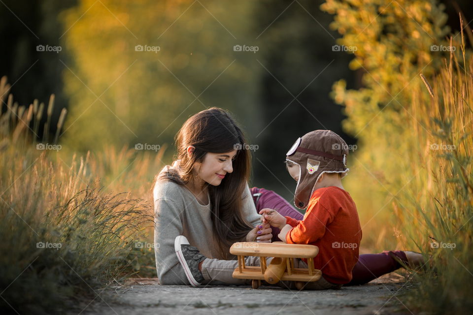 Mother and son with wooden plane at sunset