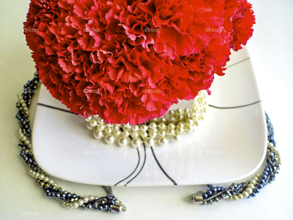 Pink carnations on a white plate with pearls