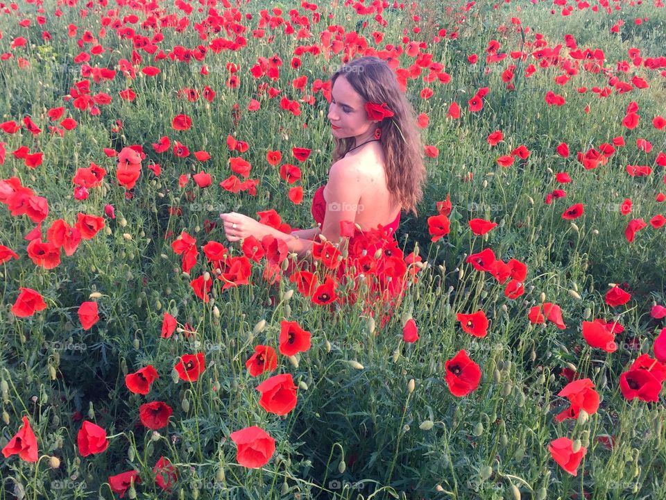Woman in  red dress in a field of poppies