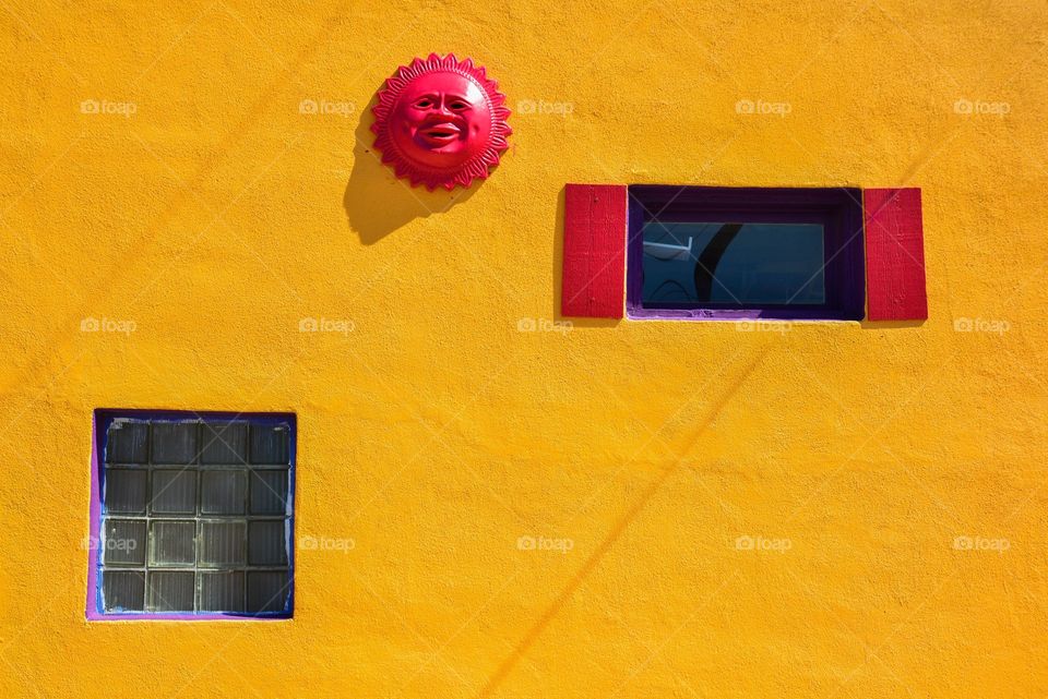 Yellow colored wall with red sun and purple window