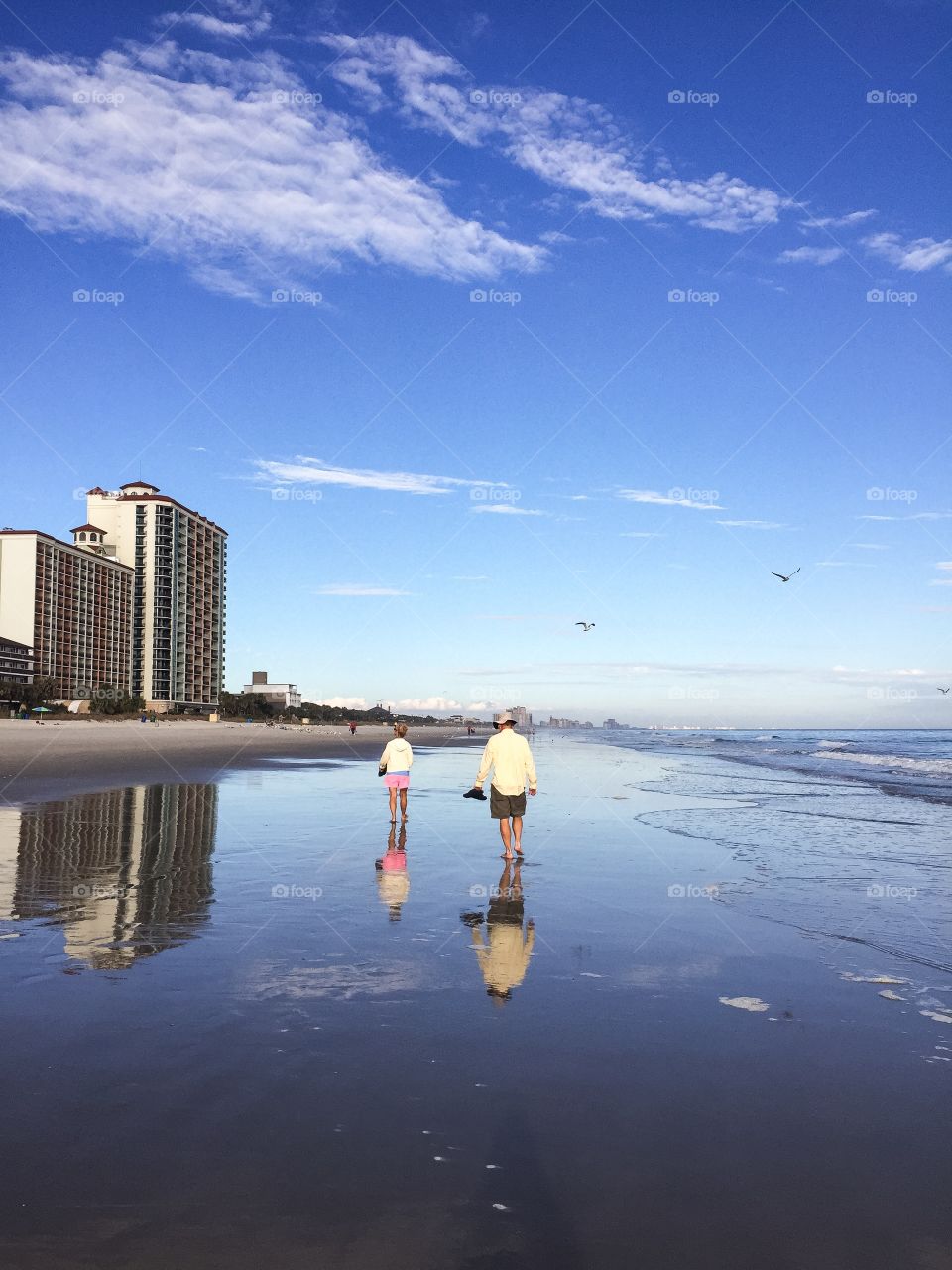 A couple strolls down the beach on a gorgeous afternoon. 