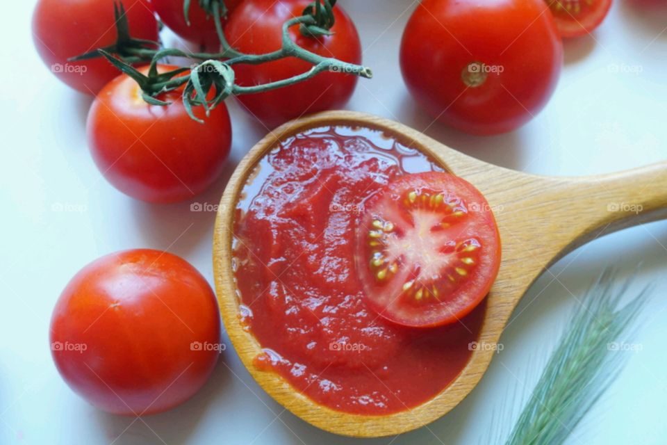 Tomatoes pickle in wooden spoon