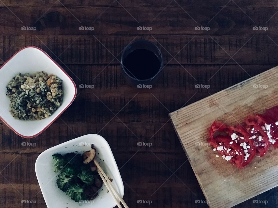 Healthy Mediterranean meal with delicious tomatoes and vegetables and grains, served with red wine on a wood table 