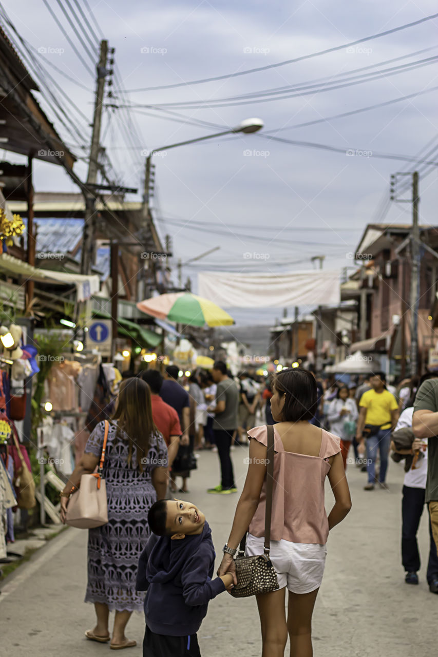 Mother and son on the street and blurry tourists at Walking Street Chiang Khan, Loei in Thailand.