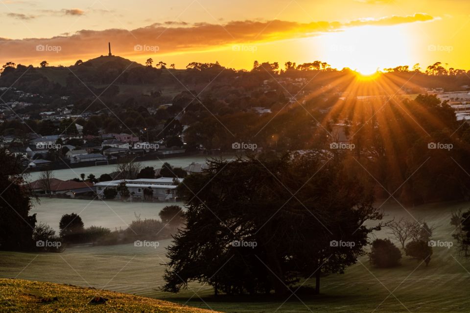 Beautiful warm sunrise with starburst over the misty valley in Auckland New Zealand 