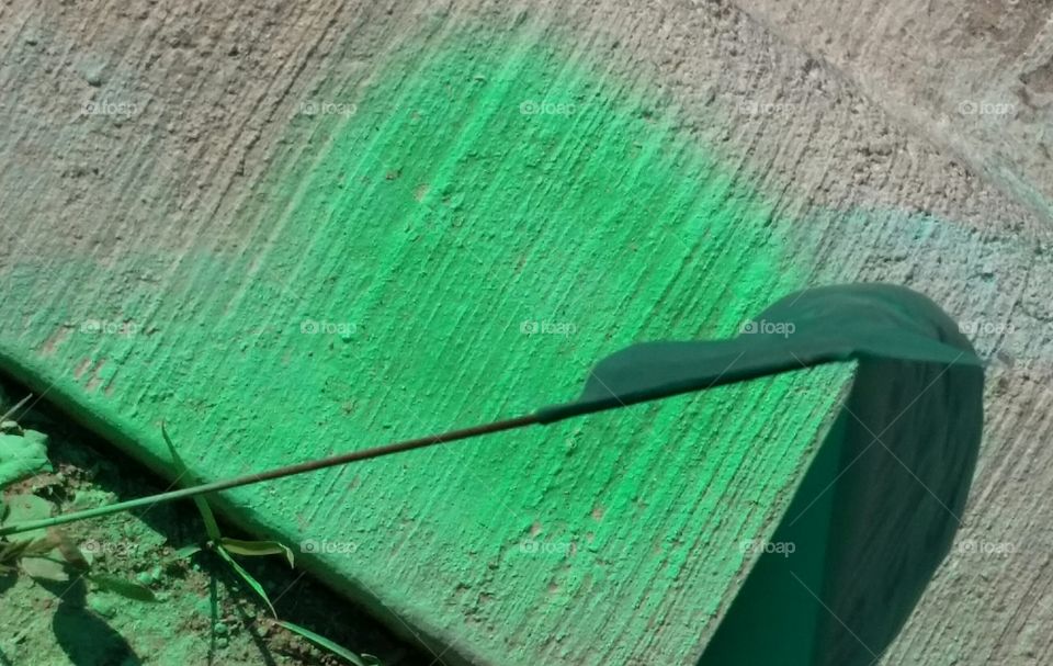 green paint on concrete with stick