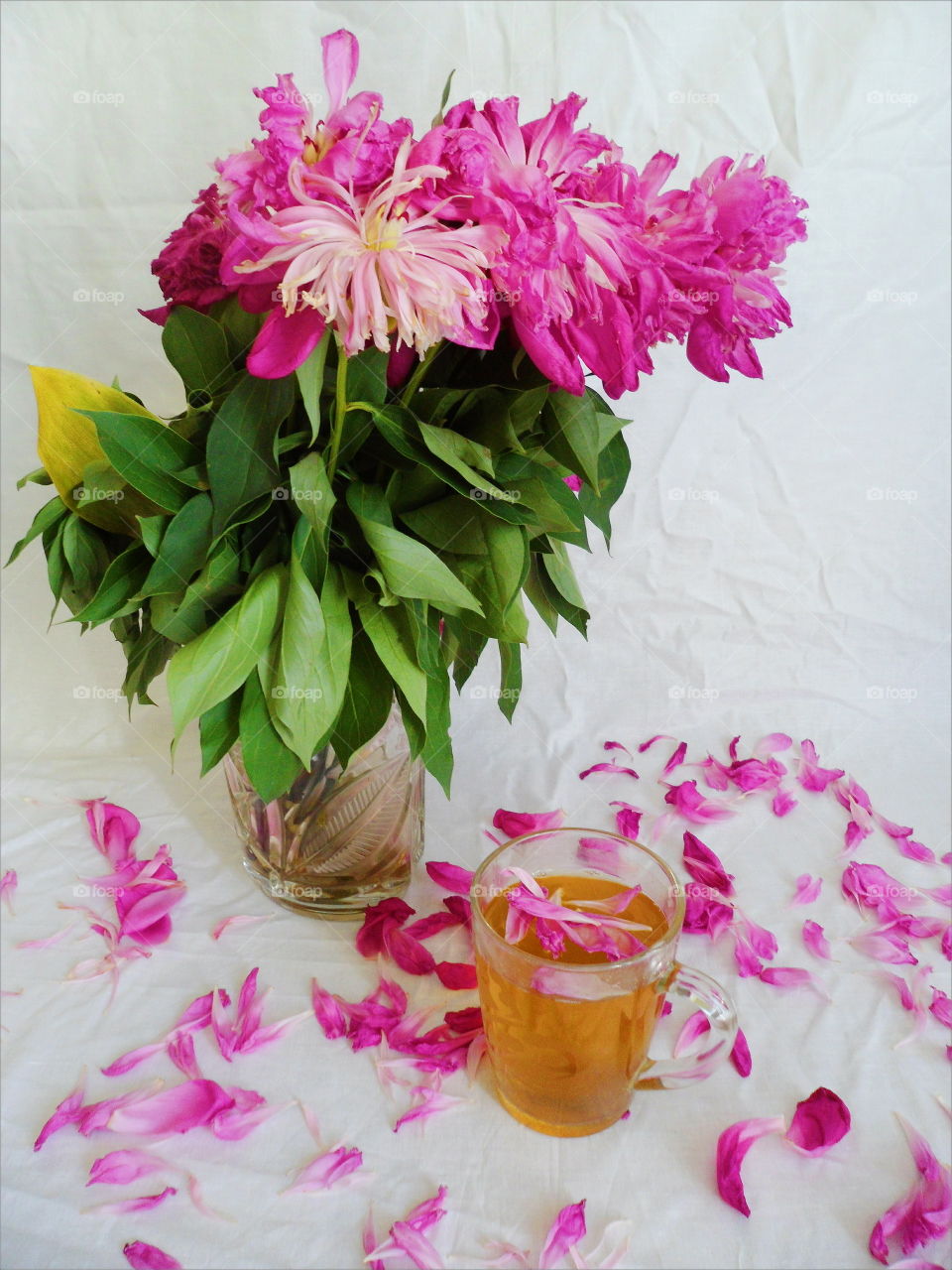 pink bouquet of wilted peony flowers and a cup of green tea