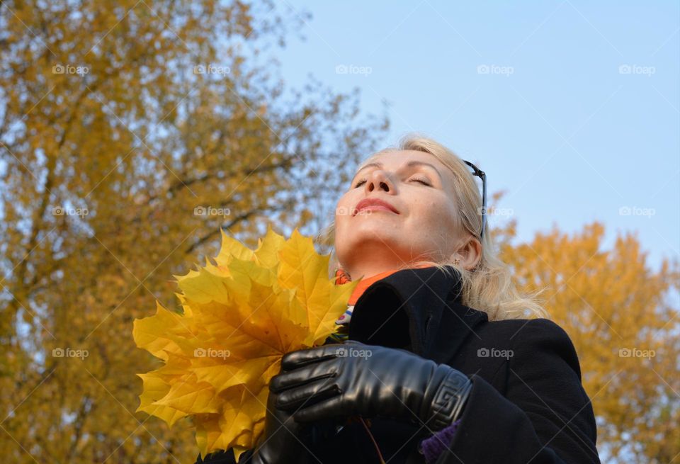 woman with yellow leaves relaxing on a nature, love autumn colours