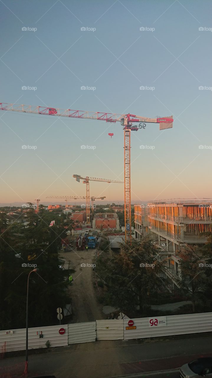 Sunrise/ sunset cranes and building site with clear blue sky