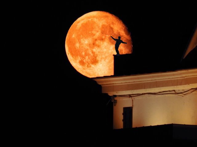 Silhouette of a man on the roof against the background of the moon