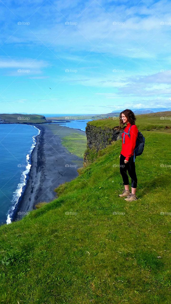 Smiling woman standing on cliff looking at view