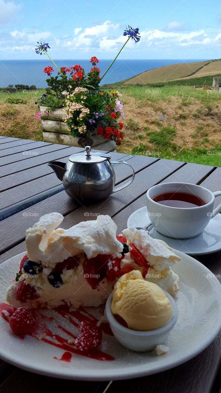 Summer mood, tea time, tasty ice-cream and cake Pavlova. Beautiful view.