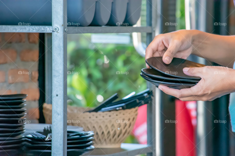 Hand holding a black plate And the dish rack.